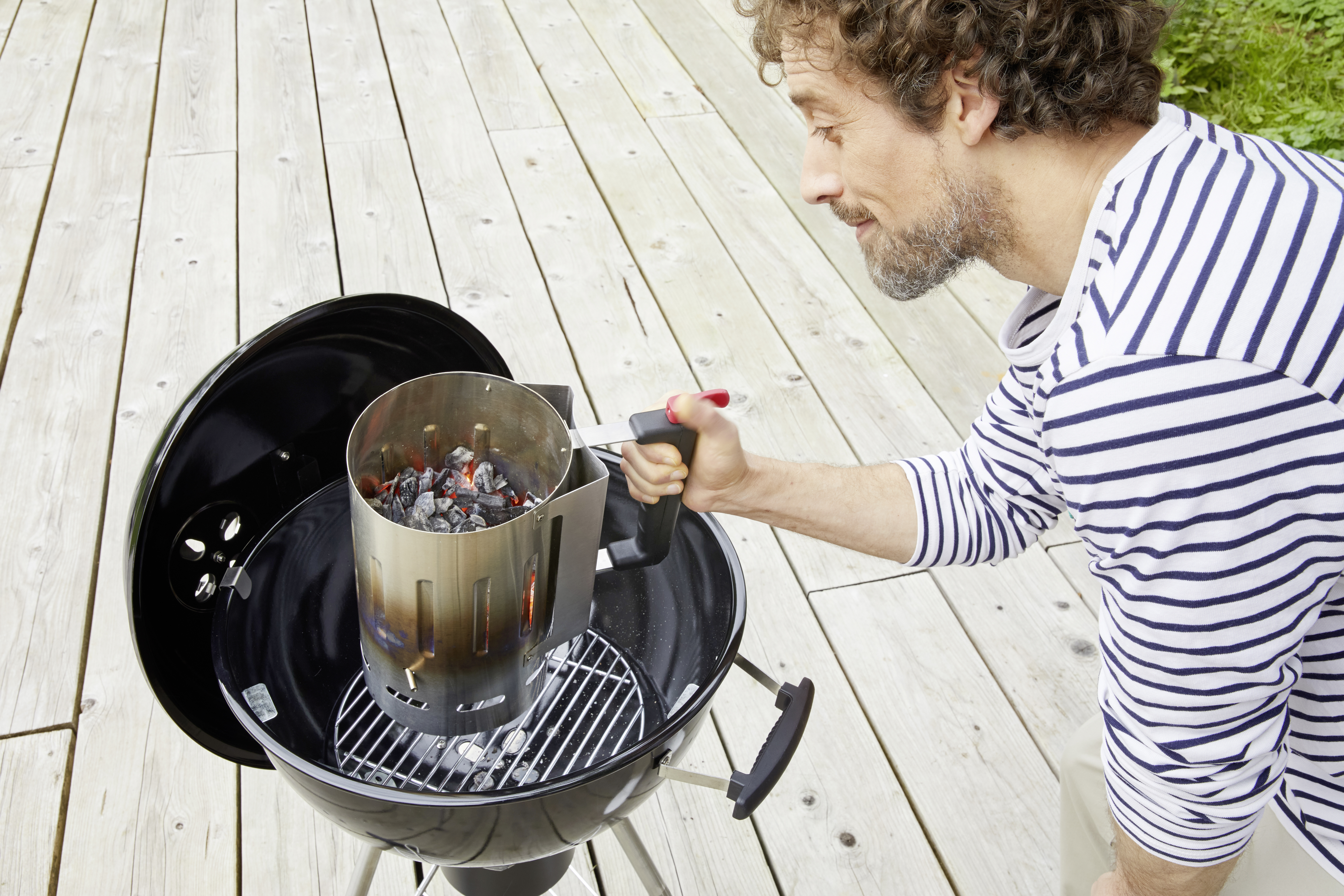 Ein Anzündkamin im Grill der gerade von einem Mann benutzt wird