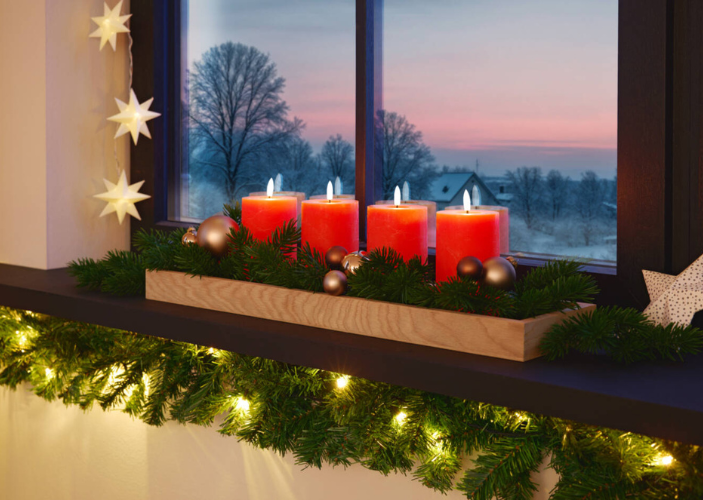 Adventskranz mit roten Kerzen auf einer geschmückten Fensterbank