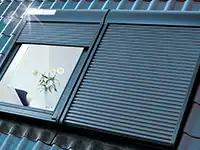 Ein Dachfenster mit geschlossenen Rollläden neben einem weiteren mit geöffneten Rollläden.