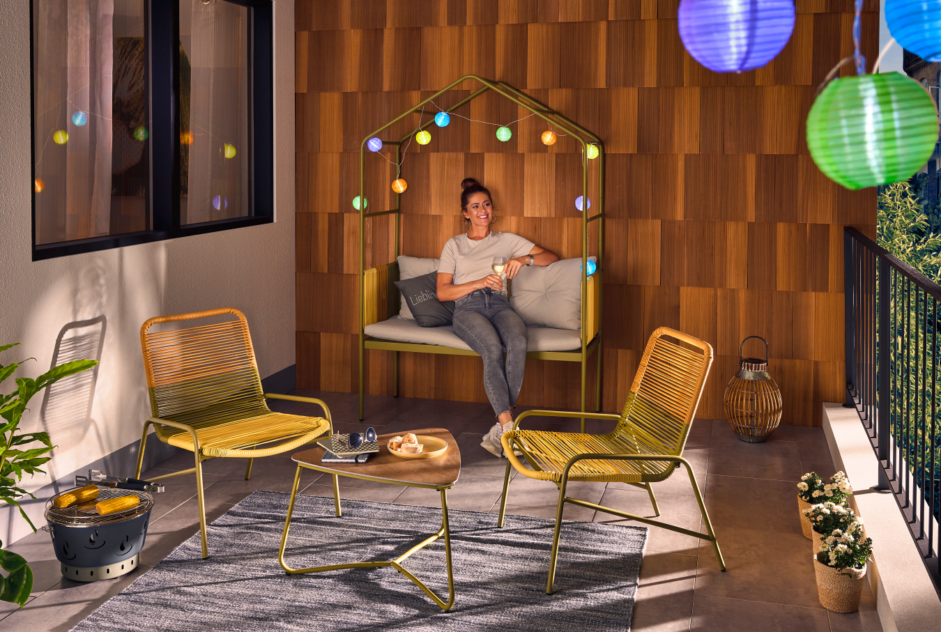 Eine Frau die auf dem Balkon sitzt der mit Lichterketten dekoriert ist